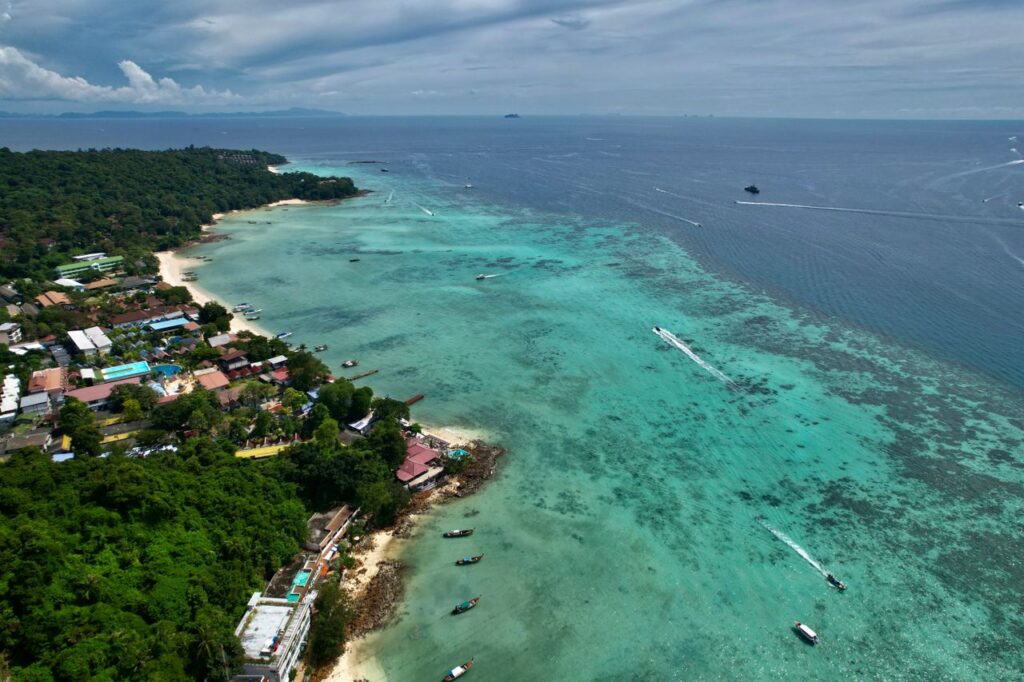 Thailandia e Malesia Da Bangkok a Kho Lipe A breathtaking aerial view of a tropical coastline with clear turquoise waters and lush greenery.