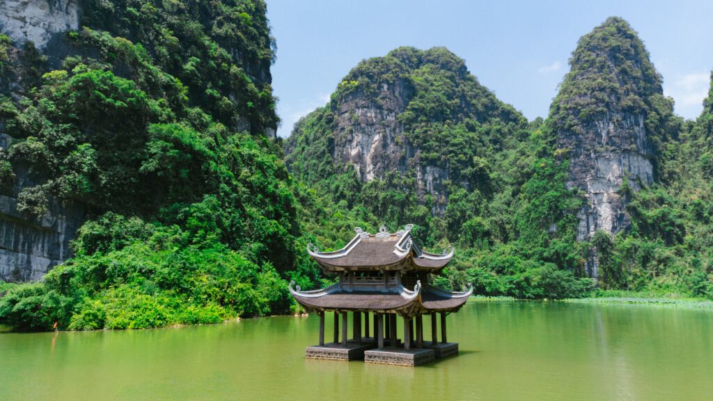 Ninh Binh Vietnam Floating pagoda amidst lush karst mountains in Ninh Bình, Vietnam, on a sunny day.