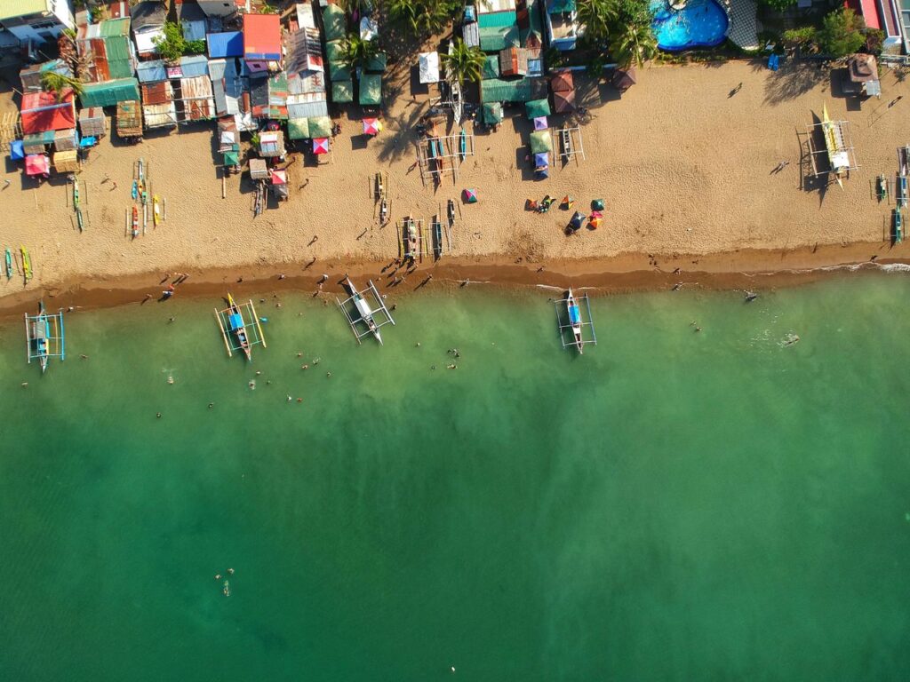 Captivating aerial view of a vibrant sandy beach with docked boats in the Philippines.