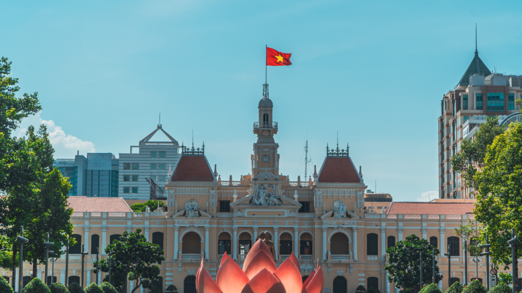 Scenic view of Ho Chi Minh City Hall featuring the Vietnamese flag under a clear blue sky.